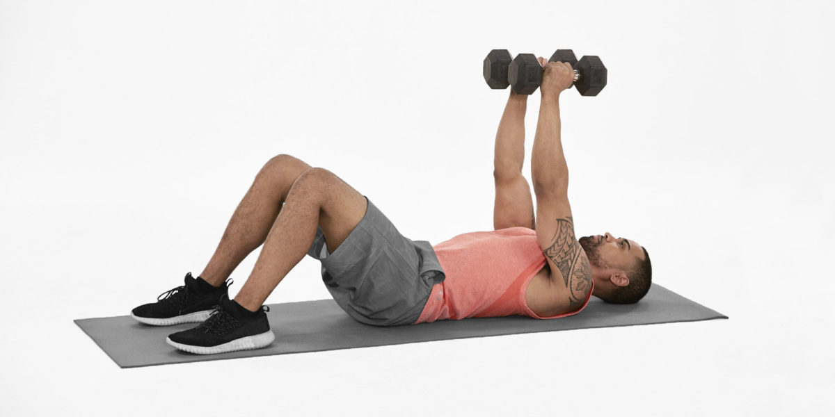 athletic man working out with dumbells on a mat.